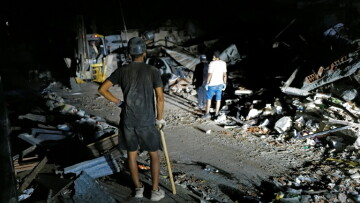 Des secouristes éclairent la zone à l'aide des phares d'un pick-up tout en recherchant d'éventuelles victimes dans un bâtiment effondré à la suite de deux séismes, à Caraballeda, dans l'Etat de La Guaira, au Venezuela, le 27 juin 2026