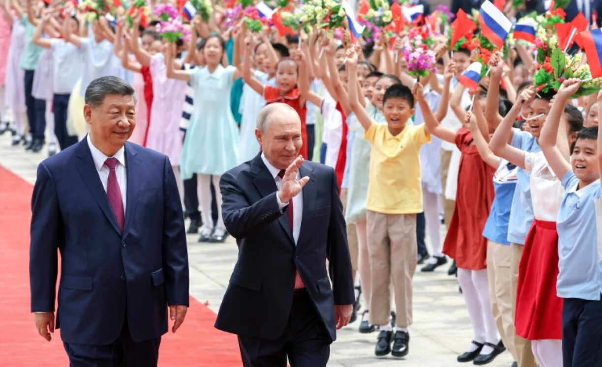 Photo diffusée par l'agence de presse russe Sputnik montrant le président russe Vladimir Poutine (d) et le président chinois Xi Jinping ors d'une cérémonie de bienveue à Pékin, le 20 mai 2026
