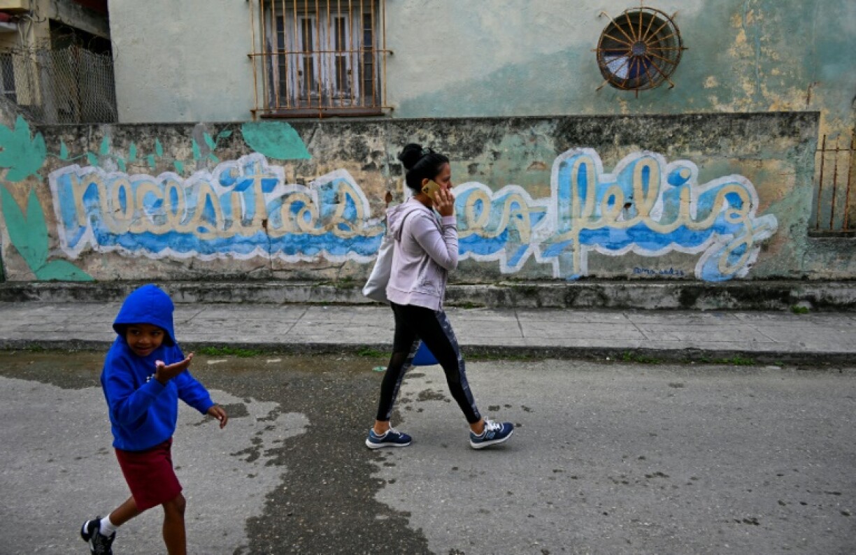 Des Cubains marchent devant le graffiti