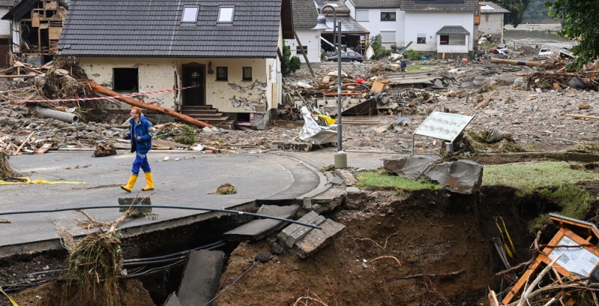 A man walks on a partially slipped road amid destroyed houses after the floods caused major damage in Schuld near Bad Neuenahr-Ahrweiler, western Germany, on July 16, 2021.