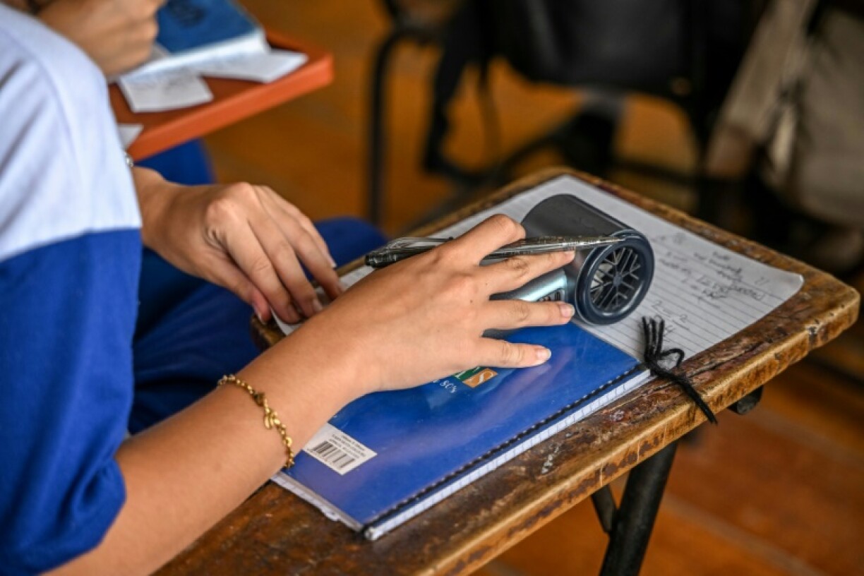 A student holding a portable electric fan during class at a high school in Baseco, Manila on March 21