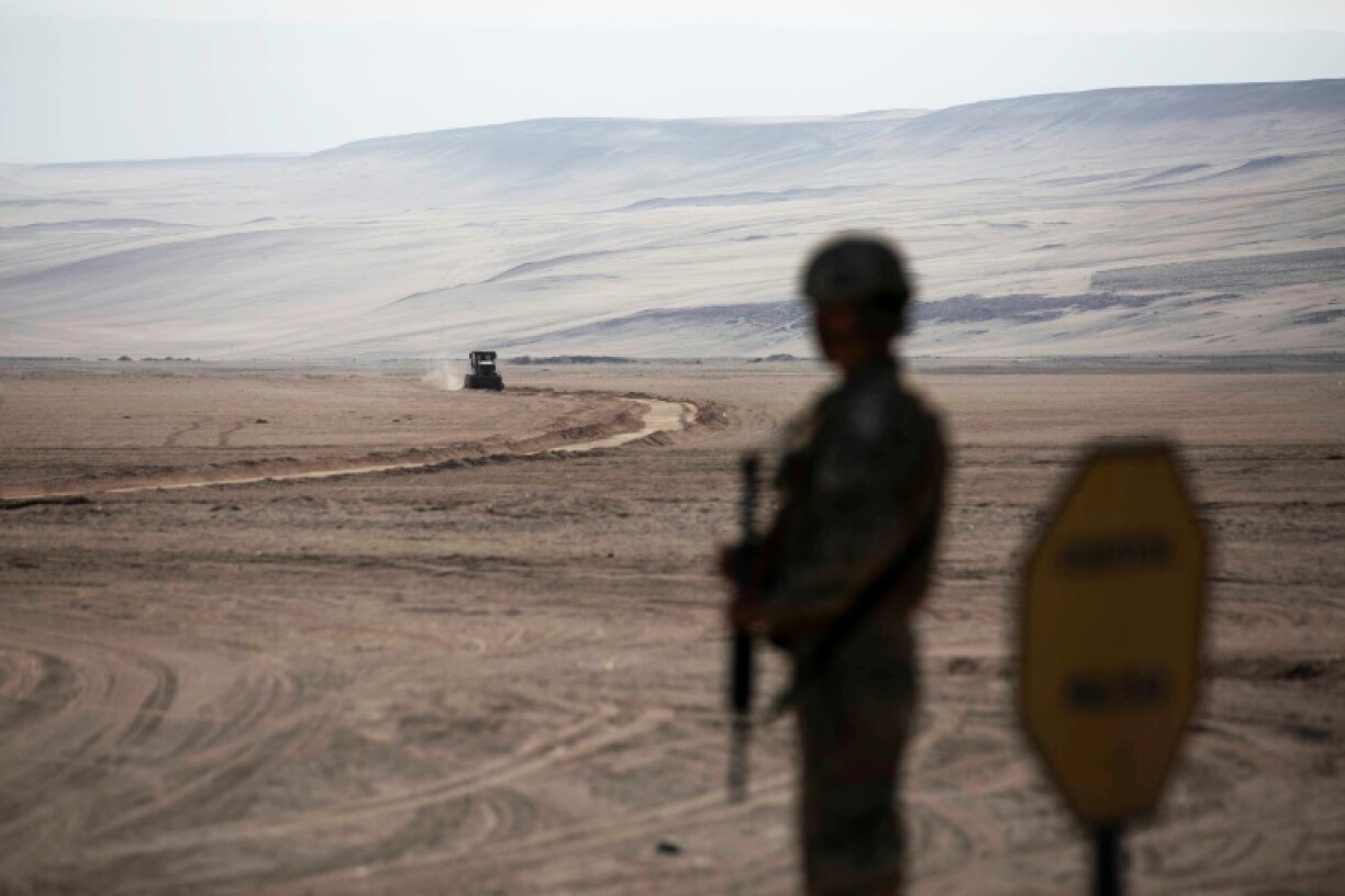 Un soldat monte la garde tandis devant des engins de chantier près du poste-frontière de Chacalluta, le long de la frontière entre le Chili et le Pérou, le 16 mars 2026