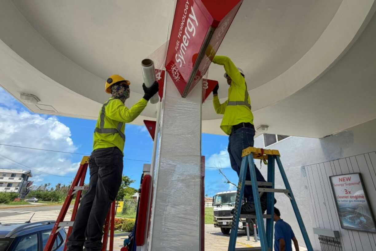 Des ouvriers consolident les panneaux d'une station service avant l'arrivée d'un "super typhon", le 4 juillet 2026 à Saipan, dans les Iles Mariannes du Nord