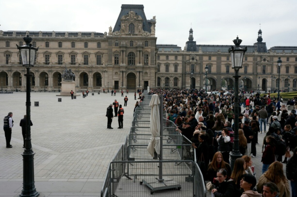 Visitors wait outside a cordoned-off area as protesters, including students from the Ecole du Louvre, block the entrance to the museum