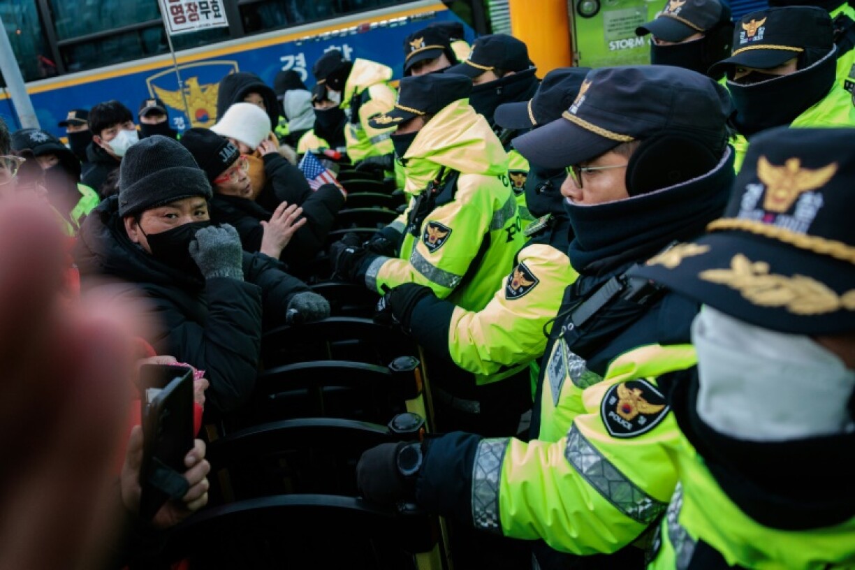 Police officers stand at a barricade with supporters of impeached South Korean President Yoon Suk Yeol