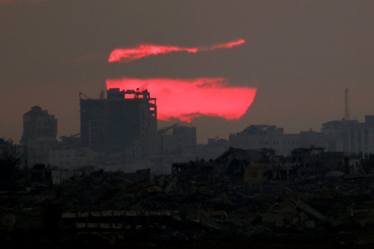 The sun sets behind destroyed buildings in the besieged Palestinian territory of Gaza on July 3, 2025