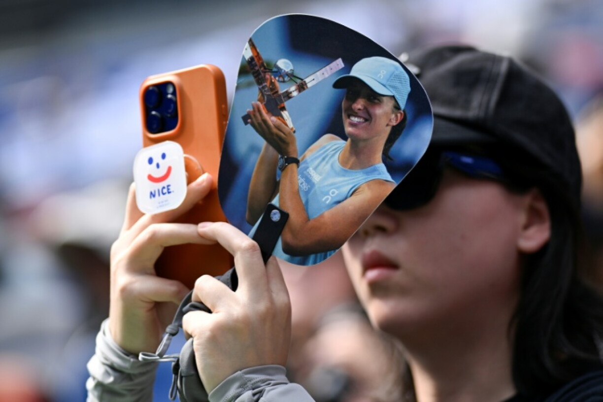 A fan of Iga Swiatek uses a mobile phone to take a picture