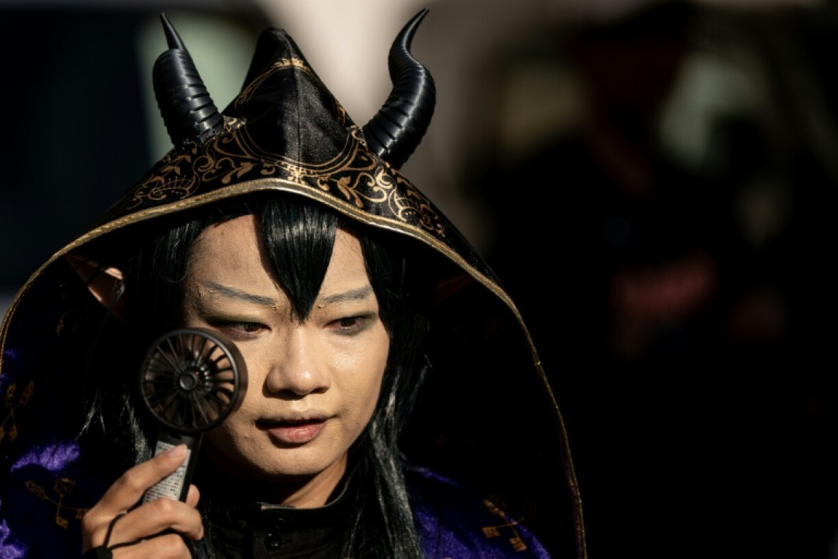 Une personne déguisée utilise un ventilateur portable pour se rafraîchir dans la rue, lors de la deuxième journée du World Cosplay Summit 2026 à Nagoya, le 1er août 2026