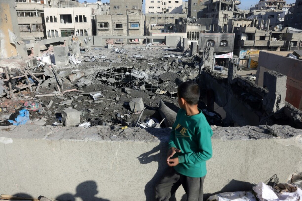 Un enfant palestinien debout sur un toit regarde la destruction après une frappe israélienne qui a touché une école transformée en abri pour déplacés dans la ville de Gaza, le 13 avril 2025