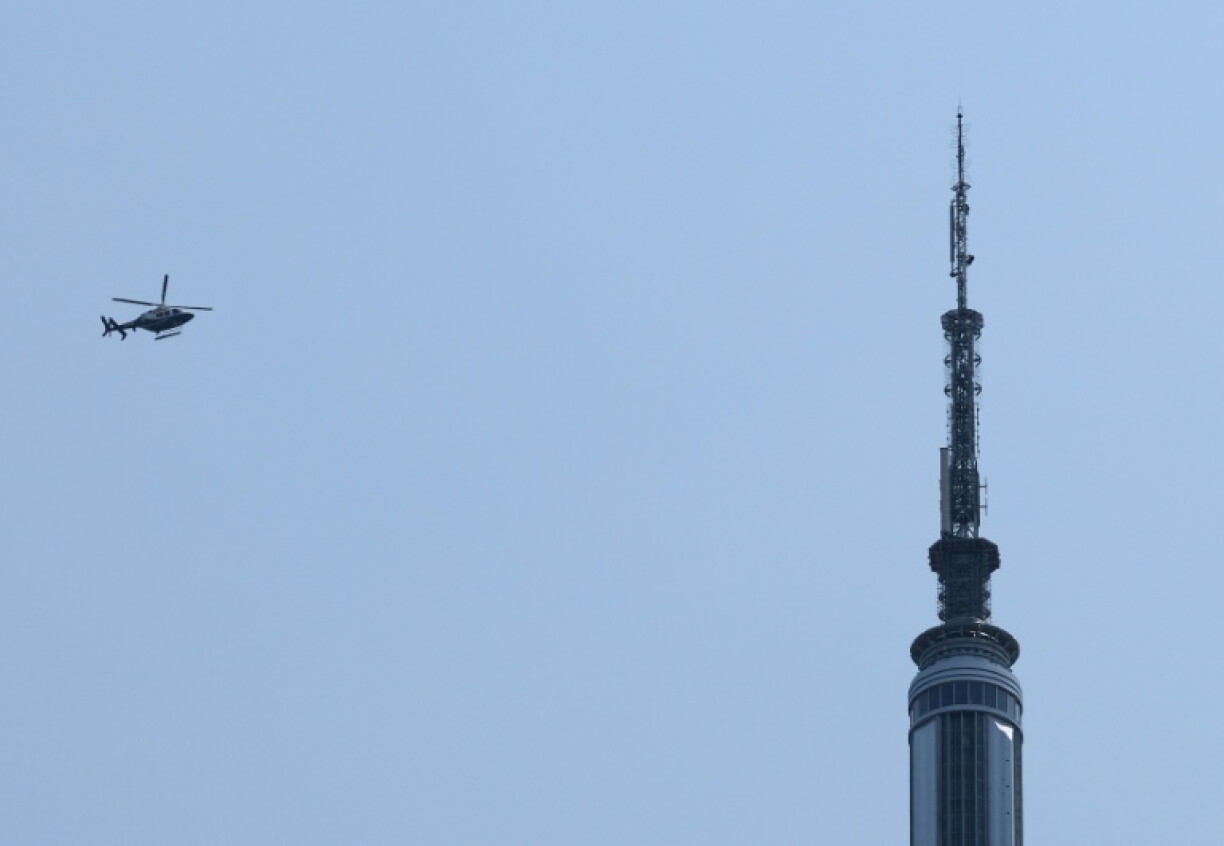 Un hélicoptère vole à proximité de l'Empire State Building où deux personnes ont escaladé le sommet de l'antenne, le 1er juillet 2026 à New York, avant d'être interpellées par la police