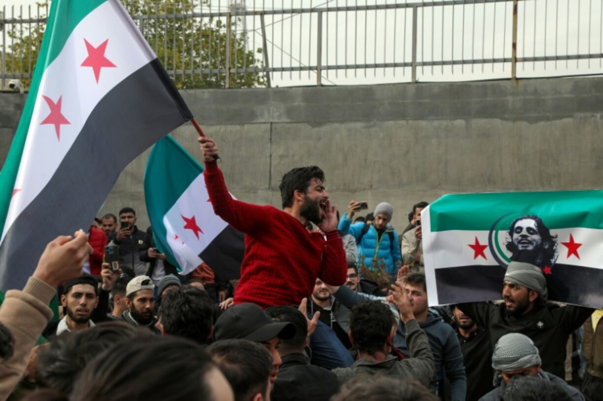 Syrians wave opposition flags, one with the portrait of late rebel fighter Abdel-Basset al-Sarout in Arbil, in the capital of Iraq's northern autonomous Kurdish region, after rebels captured the Syrian capital