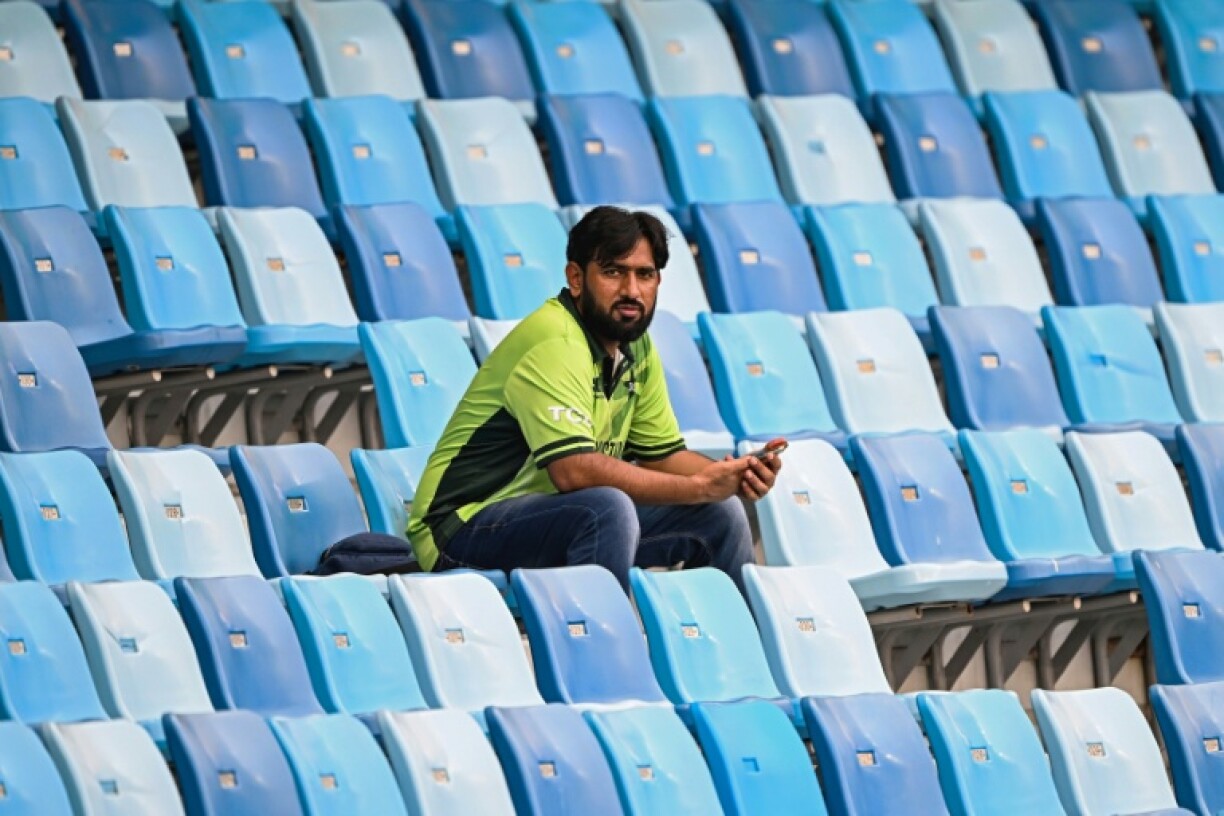 A cricket fan sits amid empty seats at the Dubai International Stadium