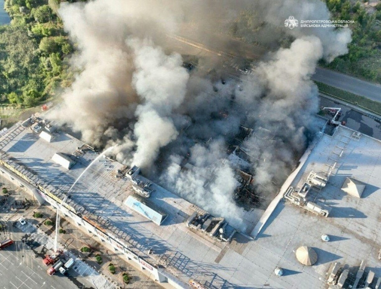 Photo diffusée par l'administration militaire régionale de Dnipropetrovsk, le 21 août 2026, montrant des pompiers luttant contre un incendie sur le site d'un centre commercial endommagé par une frappe russe à Kryvyï Rig, en Ukraine
