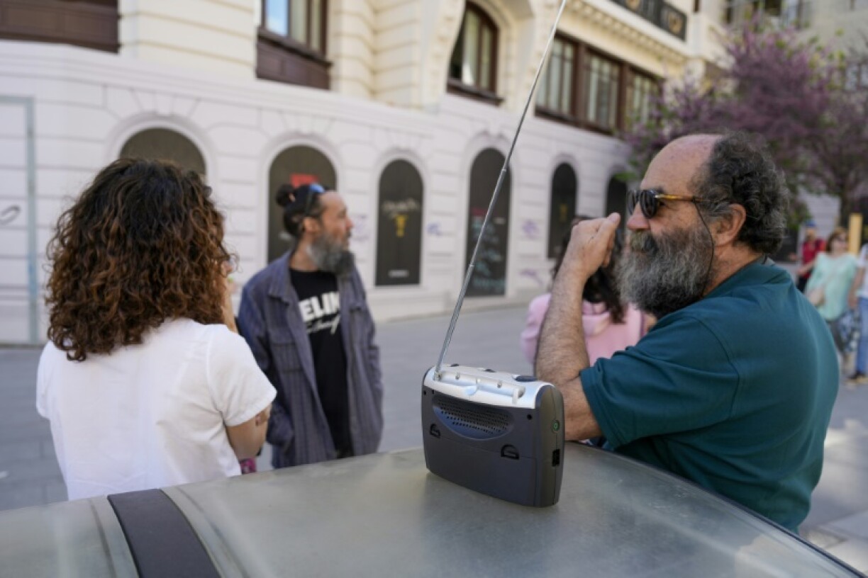 Residents gather around a battery-powered radio to listen to news during a power cut in Madrid on April 28, 2025