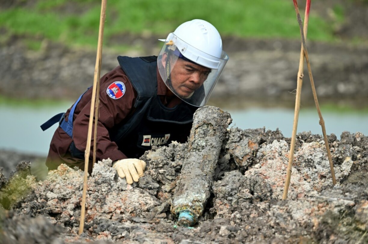 A deminer from the Cambodian Mine Action Centre examins an unexploded bomb unearthed by a worker during irrigation work in Svay Rieng province in early February 2025