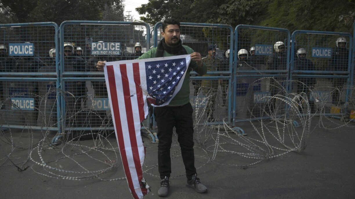 A protester holds a burned US flag during a demonstration near the US consulate following a US airstrike that killed top Iranian commander Qasem Soleimani in Iraq, in Lahore on January 3, 2020.