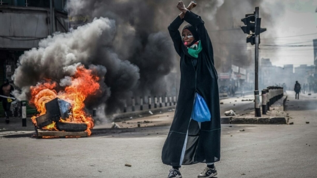 Eng Demonstrantin virun enger Barrikad zu Nairobi, déi a Flame steet.