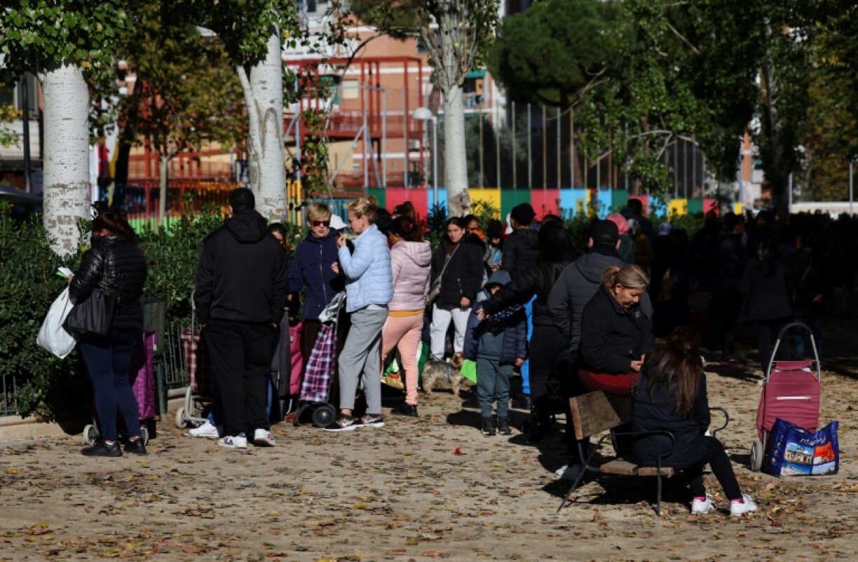 Des habitants attendent pour aller chercher de la nourriture devant le local de l'association du quartier Aluche à Madrid le 19 novembre 2022