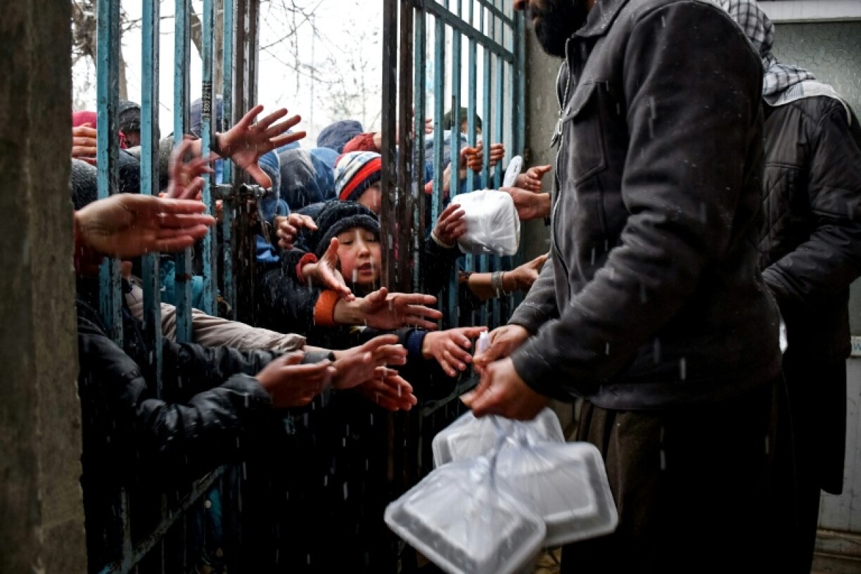 Afghan children receive food aid from a local charity in Mazar-i-Sharif on March 2, 2025