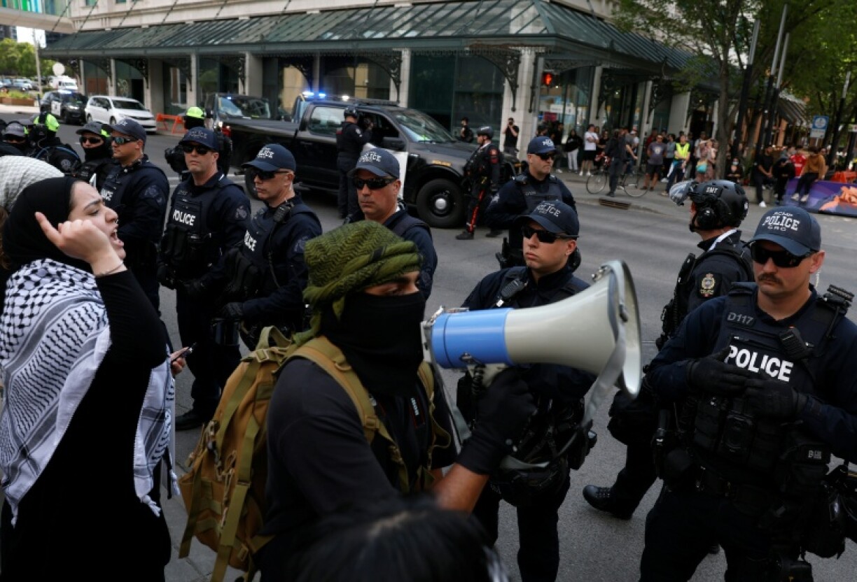 A protester uses a megaphone in front of a line of police during a demonstration in front of Calgary City Hall on June 15, 2025 as world leaders converge in Canada for the G7 Summit