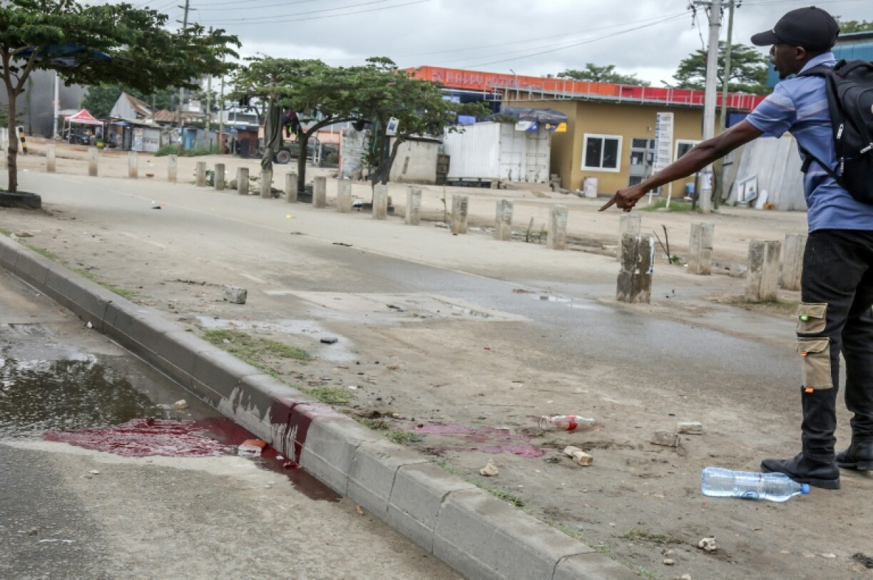 Un homme montre une mare de sang, le 29 octobre 2025, dans une rue de Dar es Salaam, capitale économique de la Tanzanie