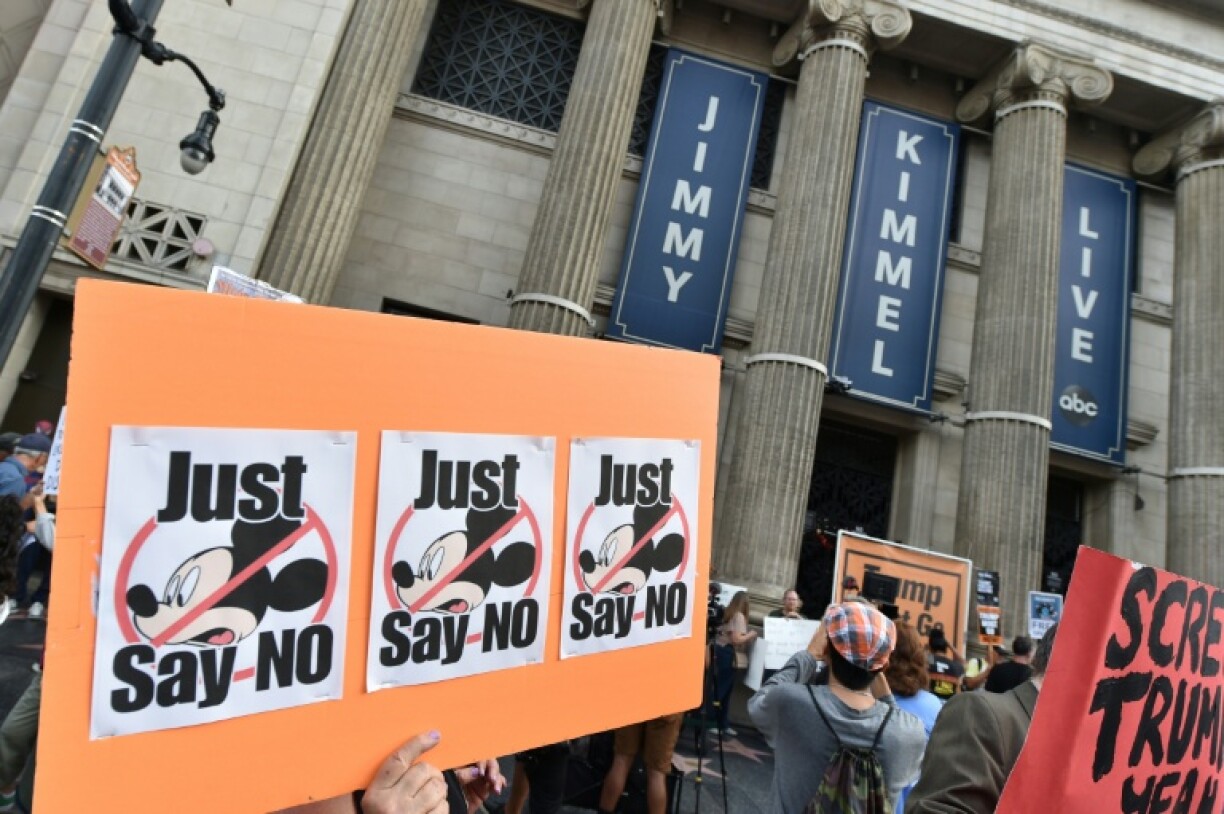 Demonstrators hold signs as they rally to protest the cancelation of the
