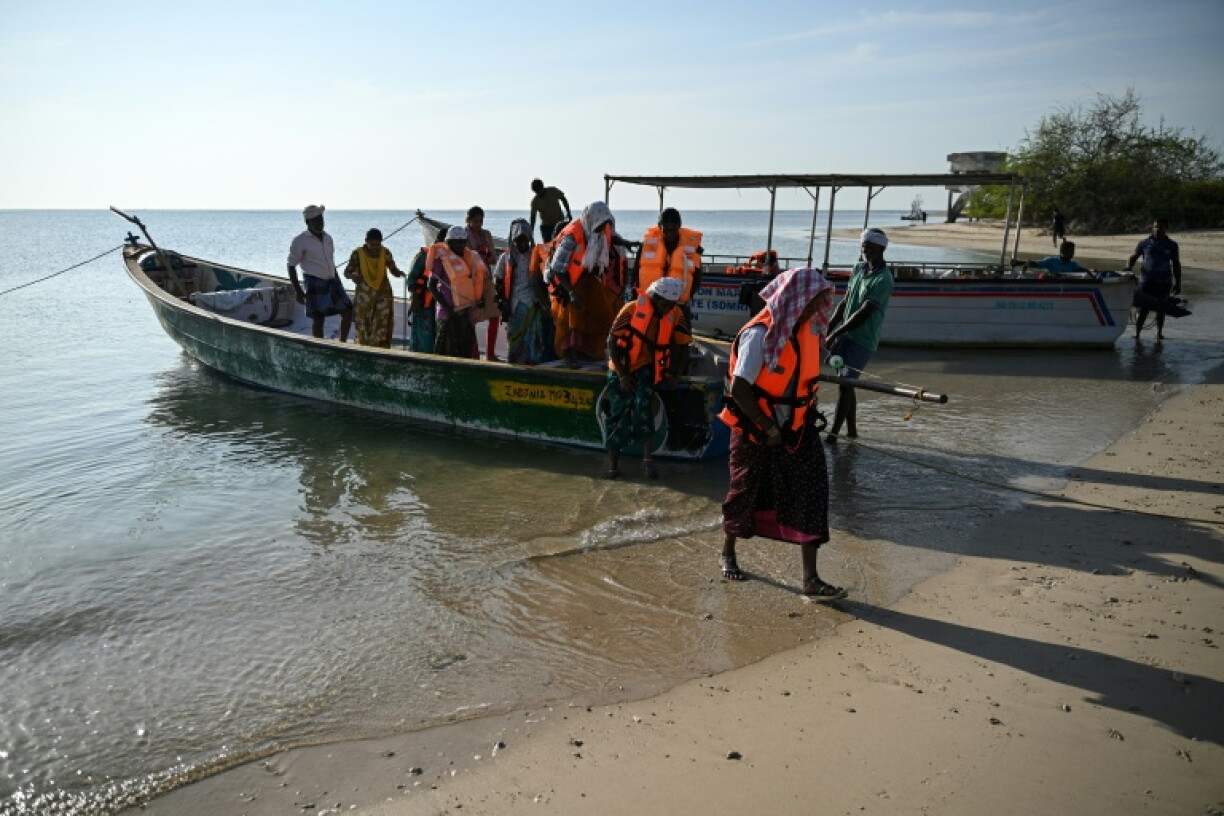 Fishing community members disembark from a boat near a shore on Kariyachalli Island