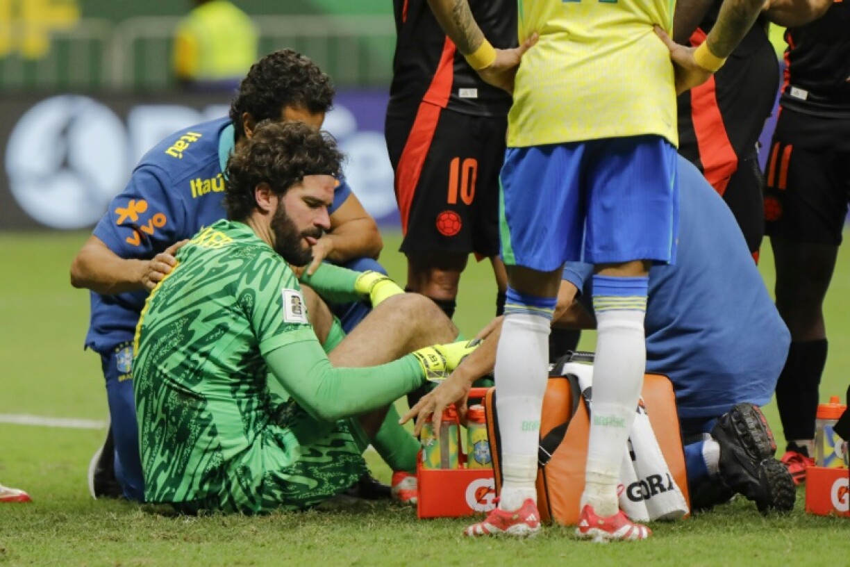 Alisson Becker receives treatment on the pitch after his collision with Colombia defender Davinson Sanchez