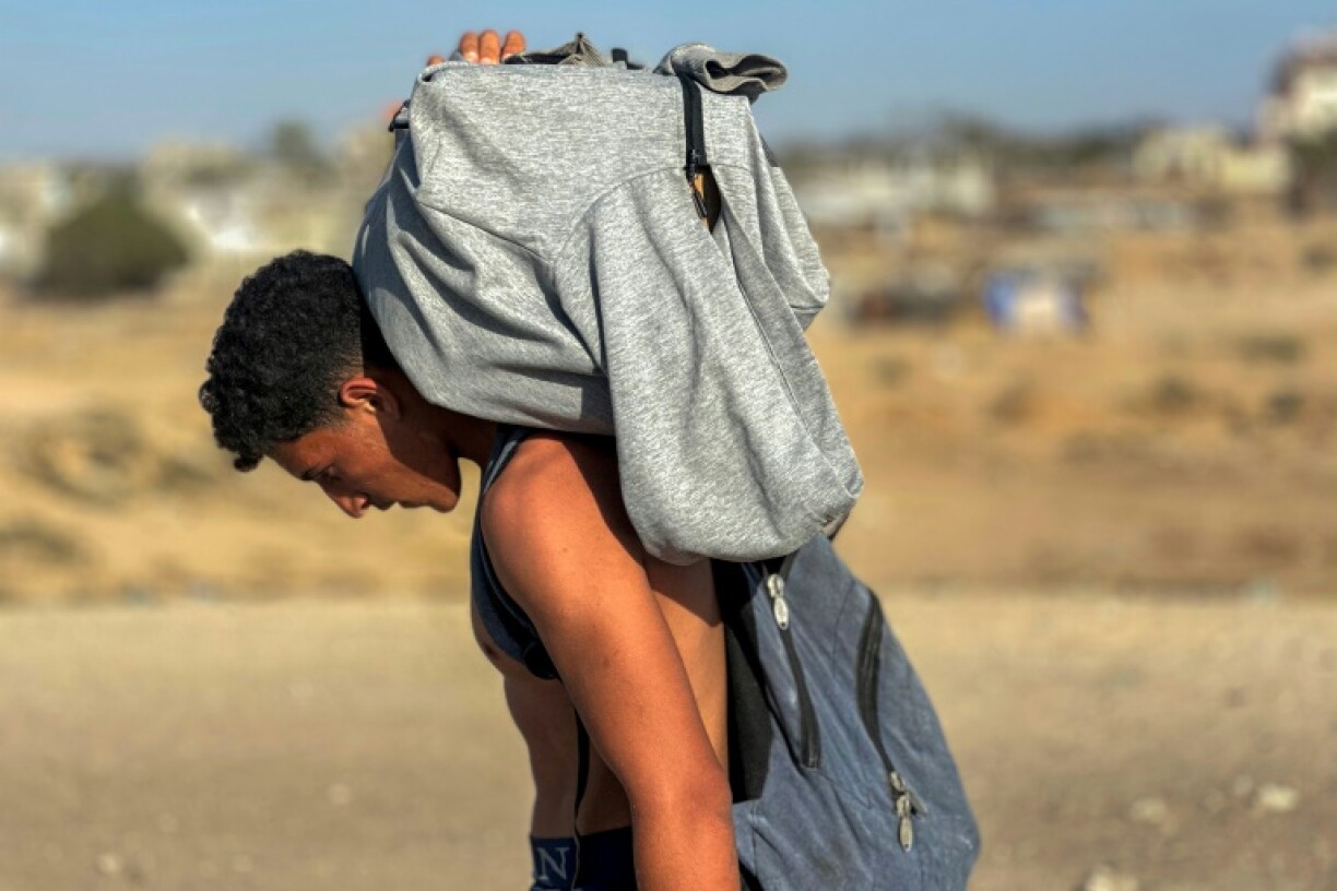 A youth carries a package on his back after Palestinians received food from a US-backed foundation in western Rafah in the southern Gaza Strip