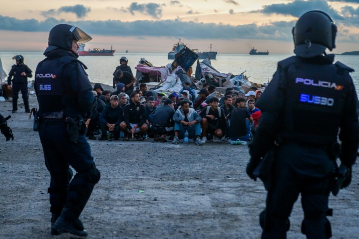 Spanish police organise migrants into groups before they are removed from a makeshift camp in Ceuta