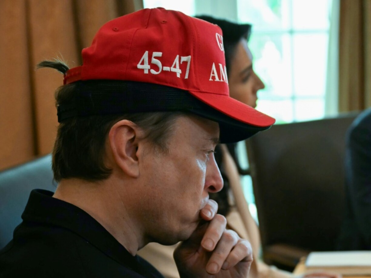 Elon Musk, wearing two hats, looks on as US President Donald Trump holds a cabinet meeting