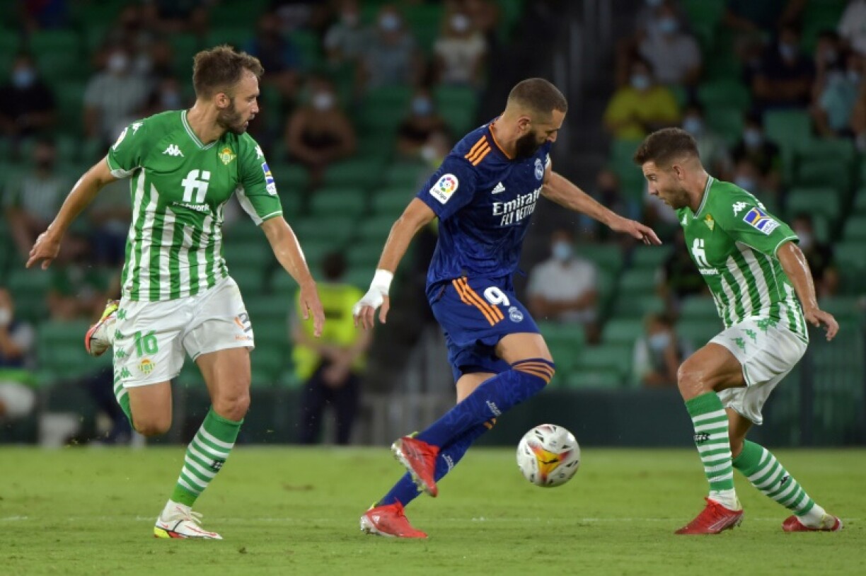 L'attaquant du Real Madrid Karim Benzema (c) entre les joueurs du Betis Loren Moron (g) et Victor Camarasa (d), le 28 août 2021 à Séville