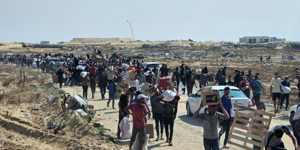 Displaced Palestinians walk along a road to receive humanitarian aid packages from a US-backed foundation in Rafah