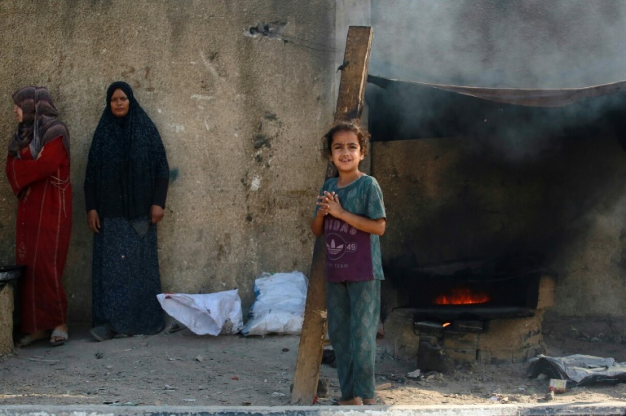 Deux femmes et une fillette palestiniennes se tiennent à côté d'un poêle allumé dans le centre de la bande de Gaza, le 13 juin 2024