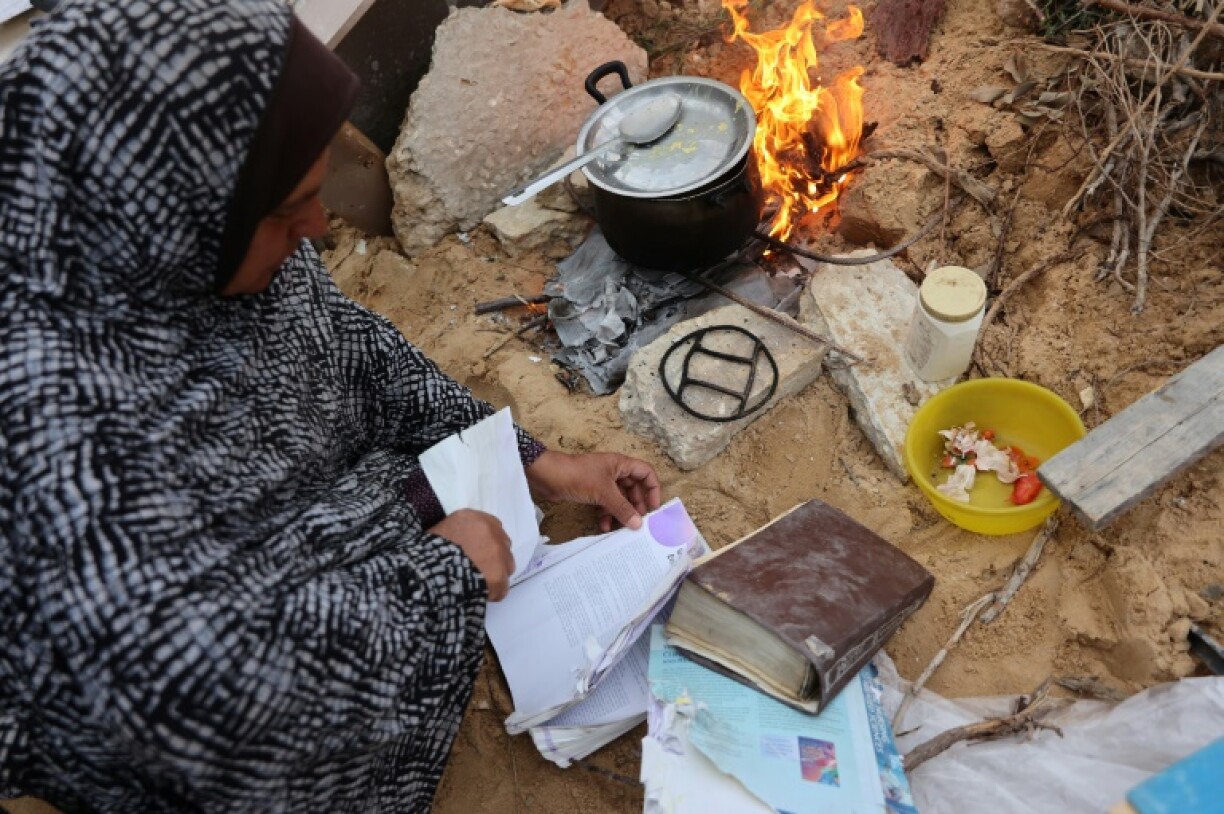 A displaced Palestinian burns pages of a book, collected from the destroyed Islamic University, to cook a meal in Gaza City