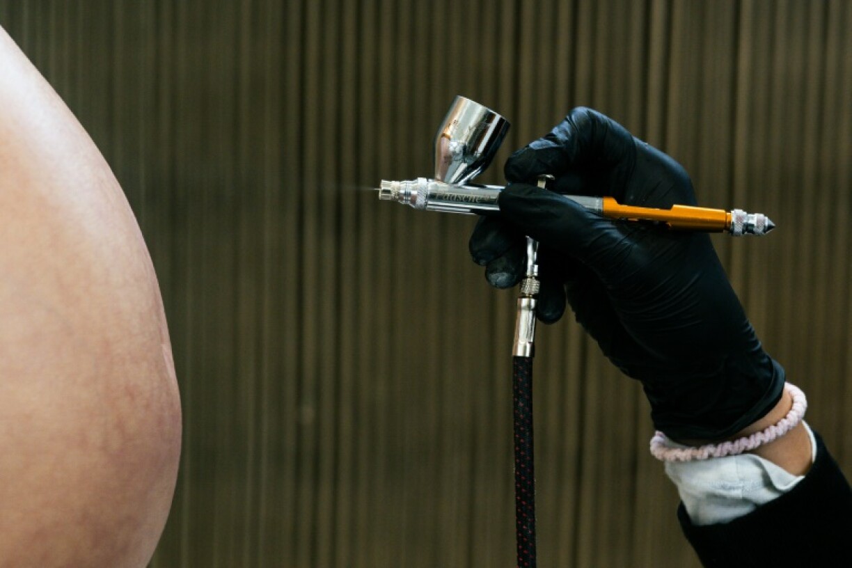 An employee paints on a fake pregnant belly made for cinema and television created by Cinebebe in Paris