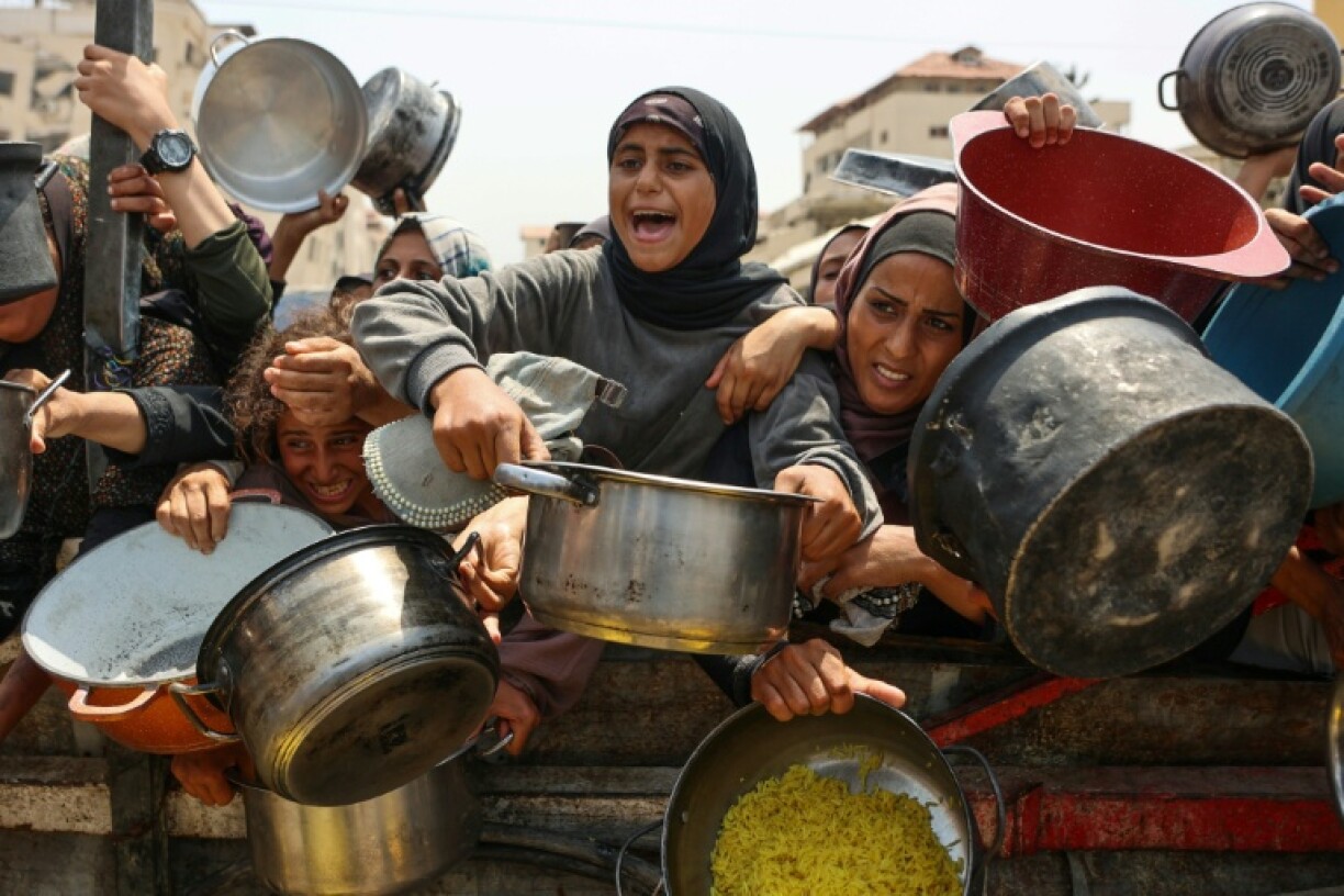 Palestinians scramble to receive cooked meals from an aid distribution centre in Gaza City.