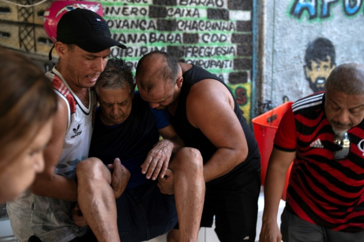 A man is assisted by neighbors after fainting due to high temperatures at the Bateau Mouche favela in western Rio de Janeiro