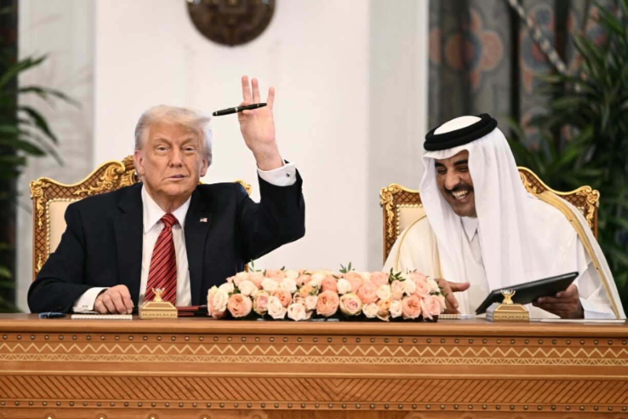 Qatar's Emir Sheikh Tamim bin Hamad al-Thani looks on as US President Donald Trump raises his pen during a signing ceremony at the Royal Palace in Doha