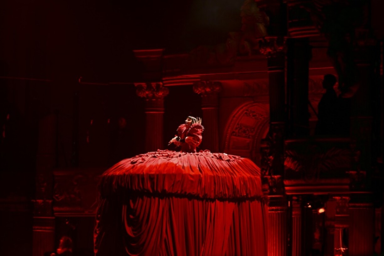 The singer kicked off the concert while perched more than two meters (6.5 feet) above the stage, sporting a massive scarlet hoop gown