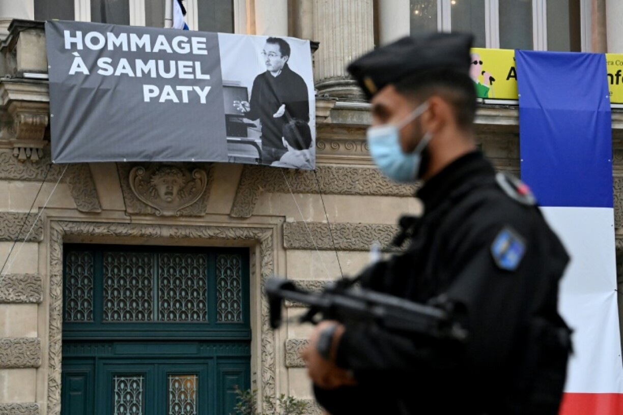Un policier devant un portrait de Samuel Paty affiché sur la façade de l'Opéra Comédie à Montpellier le 21 octobre 2020, cinq jours après son assassinat