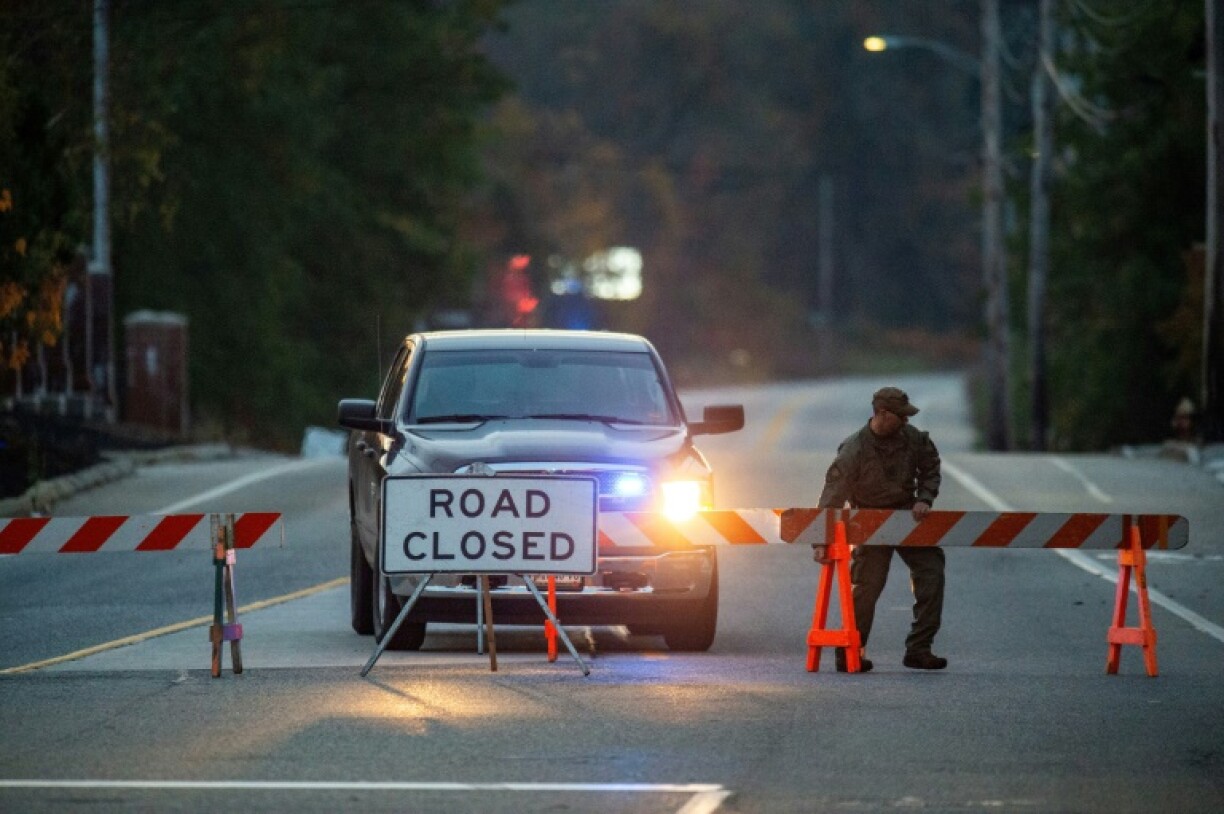 A law enforcement official moves a road block into place closing access to Schemengees Bar where a shooting took place in Lewiston, Maine