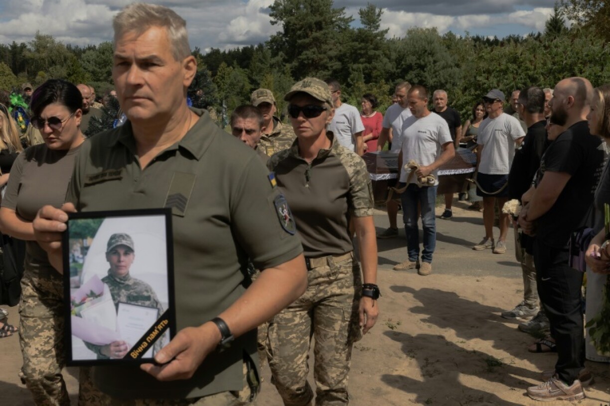 A Ukrainian military member carries a portrait of late Ukrainian soldier of the Unmanned Systems