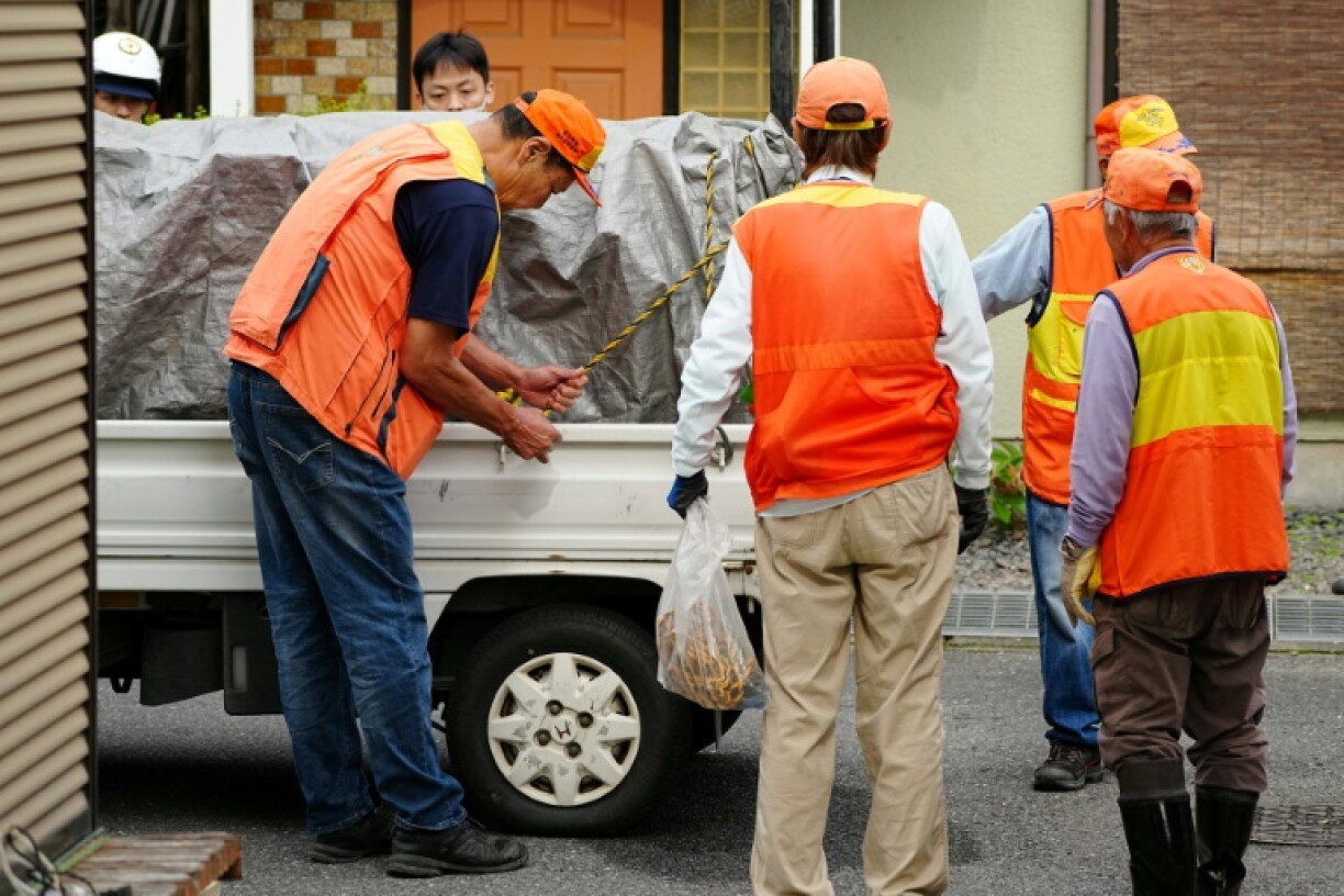 Des chasseurs se tiennent près d'un camion transportant un ours sauvage sous sédation après sa capture à Utsunomiya, au nord de Tokyo au Japon, le 9 juin 2026