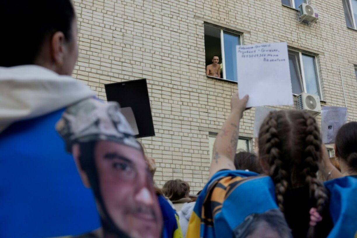 Desperate relatives show photographs of missing soldiers to a Ukrainian prisoner freed in an exchange with Russia