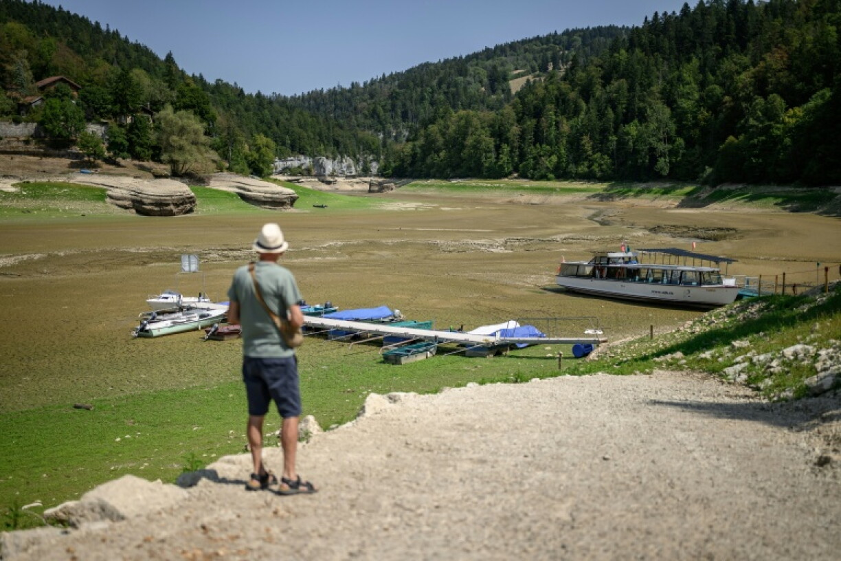 A tourist looking at the parched bed of the Lac des Brenets, which is on the border between Switzerland and France