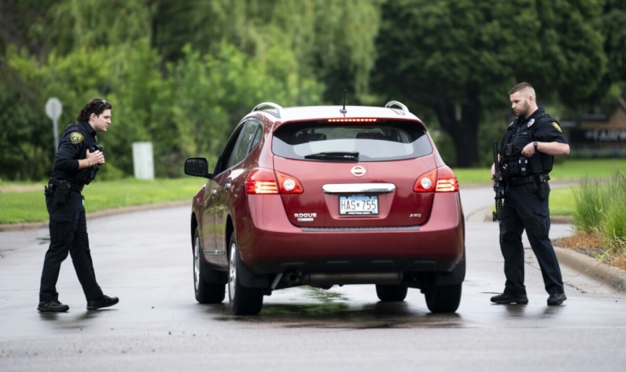 Police officers check a vehicle entering a neighborhood in Brooklyn Park, Minnesota after the shooting of two state lawmakers and their spouses