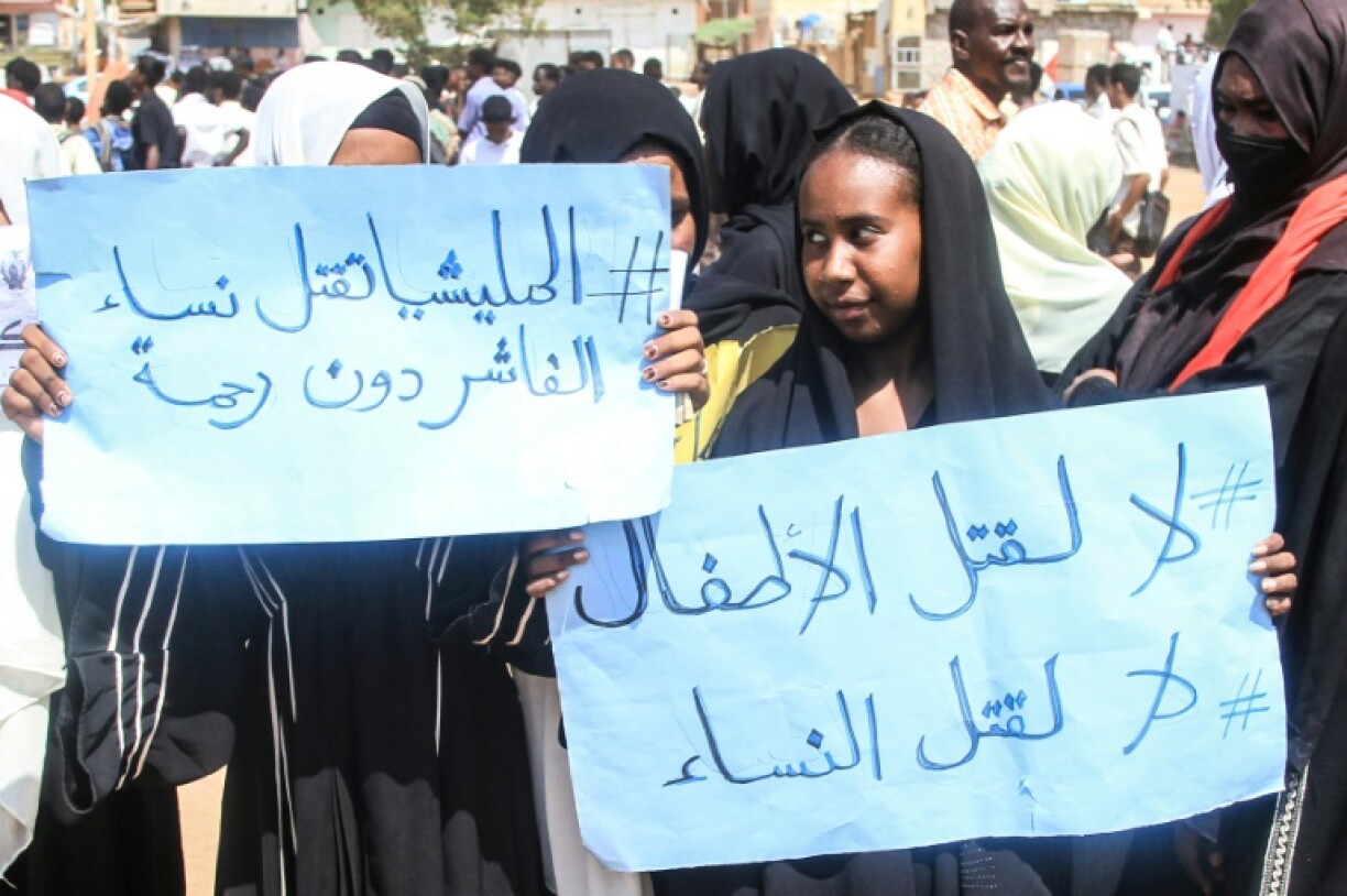 A Sudanese student in Khartoum holds a sign at a protest that reads:
