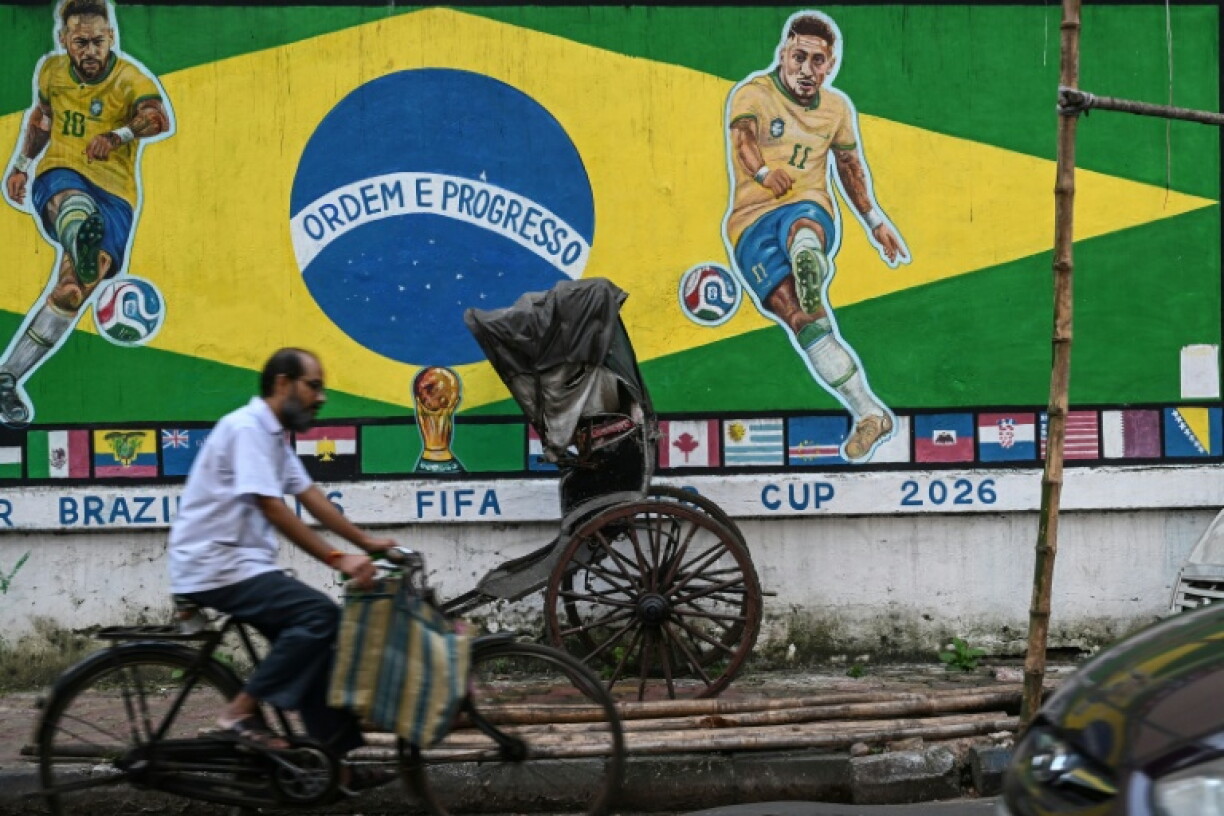 A cyclist rides past a mural featuring Brazilian football player Neymar (L) and Raphinha ahead of a FIFA international friendly football match between India and Brazil in Kolkata on September 29, 2026.