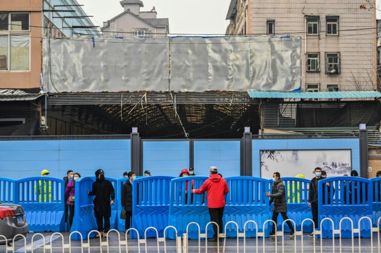 Workers place barriers outside the closed Huanan Seafood wholesale market during a visit by members of the WHO-led team investigating the origins of the Covid-19